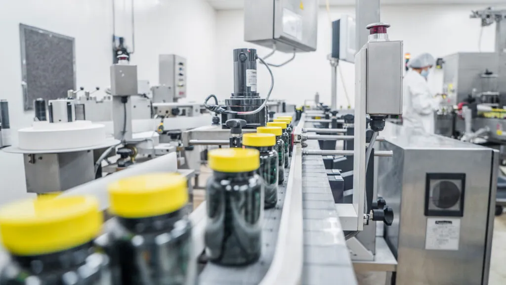 Supplement bottles moving through a GMP Pharma production line