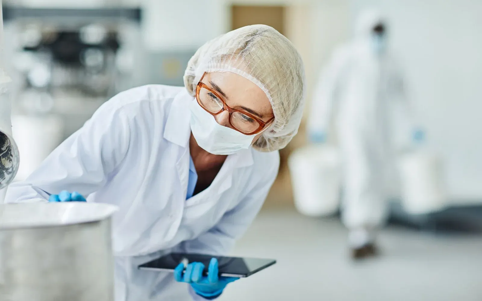 GMP Pharma quality technician performing an in-process inspection on the production line